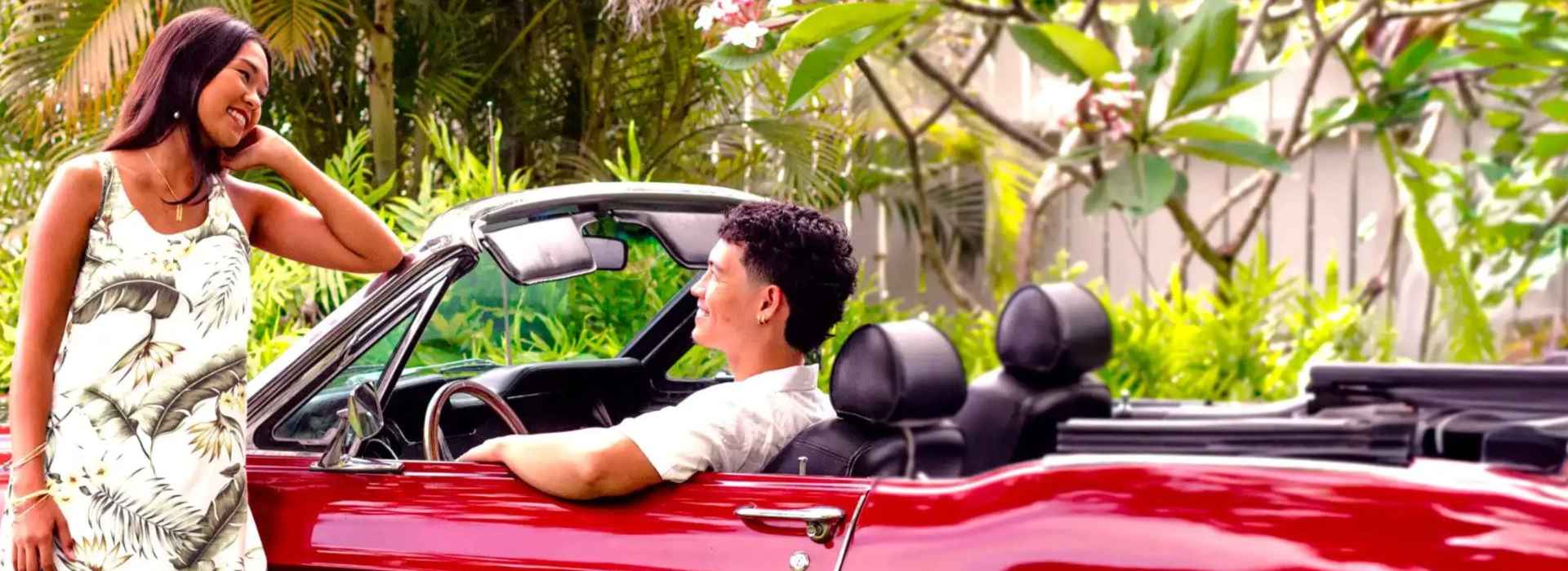 A couple wearing a beautiful short Hawaiian dress & a man's Aloha shirt from Shaka Time, ready for the weekend getaway.